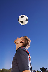 Image showing Football, bounce and head with man, training and technique with competition and exercise. Person, blue sky and player with practice for a game or athlete with skills and sports with fitness or soccer