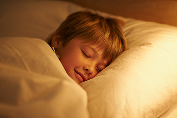 Image showing Boy, bed and rest for night, sleeping and tired with fatigue and peace. Child, dreaming and exhausted with blanket, pillow and bedroom with lamp for serene childhood at home or house for childcare