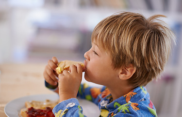 Image showing Food, breakfast and boy eating a sandwich in morning, pyjamas and home for nutrition. Children, hungry and meal for young male for lunch, childhood development and bread for health and wellness
