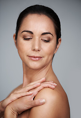 Image showing Beauty, mature and skincare of woman in studio isolated on a gray background for anti aging. Face, cosmetics and glow of model in makeup for dermatology, thinking and touch shoulder for healthy skin