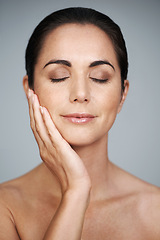 Image showing Beauty, mature and skincare of woman touching face with makeup at studio isolated on gray background. Cosmetics, glow and hand of model in facial treatment for dermatology, anti aging and eyes closed