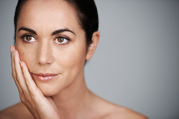 Image showing Face, skincare and mature woman in makeup at studio isolated on a gray background mockup space. Cosmetics, hand and female model in touching skin for dermatology, beauty and thinking of anti aging