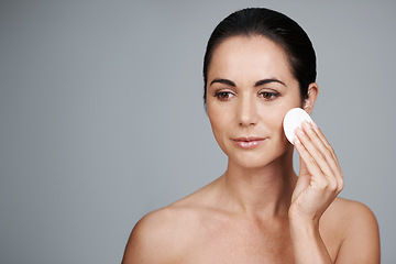 Image showing Mature woman, pad and cleanse in studio, skin care and facial treatment on gray background. Female person, cotton and swab for grooming in daily routine, mockup space and dermatology to remove makeup