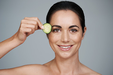 Image showing Portrait, beauty and cucumber with smile of woman in studio on gray background for natural wellness. Face, antiaging or detox and happy mature model with vegetable slice for diet, health or nutrition