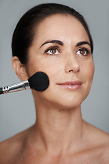 Image showing Cosmetics, brush and mature woman in studio with beauty, natural and facial glow routine. Makeup, self care and confident female person with cosmetology tool for glow isolated by gray background.