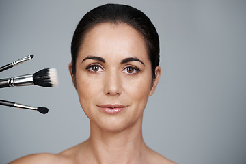 Image showing Makeup, brushes and portrait of woman in studio with beauty, natural and facial glow routine. Cosmetics, self care and mature female person with cosmetology tools isolated by gray background.