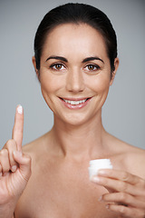 Image showing Portrait, mature and happy woman with cream for skincare in studio isolated on gray background. Face, cosmetics or model with moisturizer container for dermatology, health or hydration for anti aging