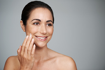 Image showing Face cream, beauty and mature woman in studio for skincare, natural and face treatment. Smile, cosmetic and female person with spf, lotion or sunscreen for dermatology routine by gray background.