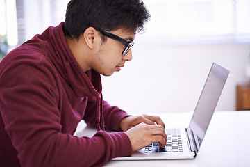 Image showing Young man, focus and typing with laptop for research, development or creative startup on table at office desk. Male person, nerd or geek with vision on computer for email, networking or communication
