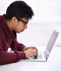 Image showing Man, focus and typing with laptop for research, development or creative startup on table at office desk. Male person, nerd or young geek with vision on computer for email, networking or communication