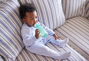 Image showing Baby, bottle or sofa for nutrition, health or growth by morning breakfast meal in living room. Hungry, black boy or mouth on couch to drink, milk or formula for early childhood progress or care