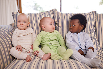 Image showing Living room, diversity and baby friends on sofa in home together for morning child development. Adorable, cute or innocent with boy and girl infant kids in onesie pajamas at apartment for bonding