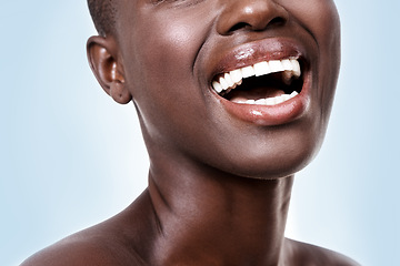 Image showing Mouth of woman, happy or laughing with beauty, cosmetics or healthy skin for shine isolated in studio. Face, closeup or funny girl model with lip gloss, smile or skincare results on blue background