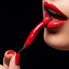 Image showing Chili, red lipstick and closeup of woman lips in studio with trendy, beauty and manicure treatment. Mouth, cosmetics and female person with nail polish eat pepper for cosmetology by black background.