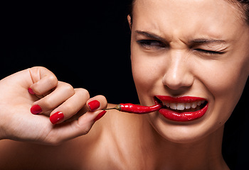 Image showing Beauty, makeup and woman eating chilli in studio with manicure on hand isolated on a black background. Cosmetics, model and person with pepper in mouth, food or healthy vegetable for skincare on face