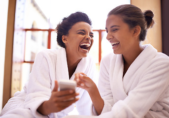 Image showing Beauty, phone and spa with women laughing in robes for luxury pampering or treatment together. Happy, app and social media with funny young friends at resort or salon for wellness or weekend getaway