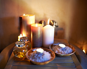 Image showing Spa, candle and oil with salt in room for peace or luxury with aromatherapy to relax, zen and meditation. Aromatic or cosmetic liquid, table and candlelight for mindfulness or wellness and self care.