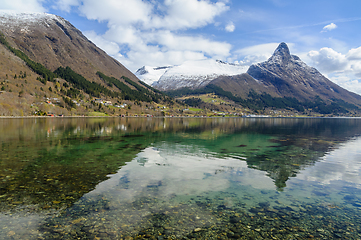 Image showing Pristine reflections on the crystal-clear sea amidst snow-capped