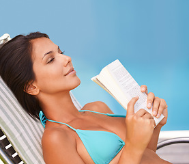 Image showing Woman, bikini and swimming pool relax with book for holiday vacation at hotel accommodation, summer or resting. Female person, swimwear and reading in Hawaii for travel resort, tanning or peaceful