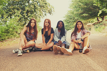 Image showing Teen, road and girl with skateboard for hobby in forest with serious look, outdoor and activity in California. Diverse group, friends and sit on street for school holiday or break, fun and together