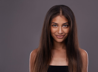 Image showing Portrait, hair care and Indian woman with cosmetics, treatment and grooming routine on a grey studio background. Face, person and model with volume or texture with keratin and healthy shine with glow