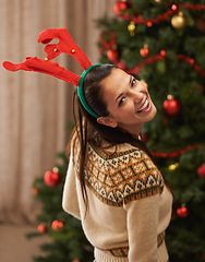 Image showing Portrait, happy and woman in home for Christmas, party or holiday in apartment in Spain. Xmas, face and smile of female person in antlers for festive celebration, funny and laughing by tree in house