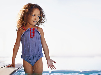 Image showing Kid, girl and water with face, swimwear and blue summer sky for relax and smile. Child, youth and sunshine with happiness, outdoor and play with curly hair and fun for sunny positivity and childhood