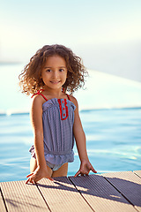 Image showing Child, girl and water with portrait, swimsuit and blue summer sky for relax or smile. Kid, youth and sunshine with happiness, outdoor and play with curly hair and fun or sunny positivity or childhood