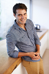 Image showing Smile, happiness and portrait of man in kitchen at home, house and apartment leaning on countertop. Interior, male person and homeowner relax on table in canteen, pantry and cooking area in Portugal