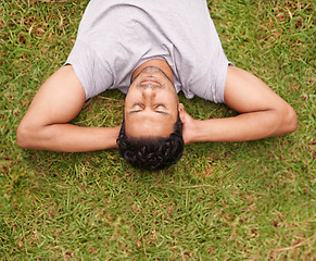 Image showing Man, outdoor and sleep on lawn, grass and eyes closed in dreaming outside for summer in nature. Male person, backyard and adult to relax, peace and vacation in garden or park for peace and calm