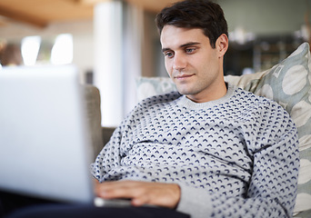 Image showing Man, living room and sofa with typing on laptop for remote work as freelance journalist for newspaper and online research. Male person, home and focus on internet to search on information for article