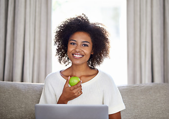 Image showing Woman, apple and laptop on sofa for snack, wellness or diet for break, vitality or eat for health at home. Freelancer, smile and tech with green fruit for vitamin and nutrition for cleanse on couch