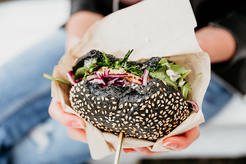 Image showing Close up of woman hands holding delicious organic salmon vegetarian burger on open air beer an burger urban street food festival in Ljubljana, Slovenia.