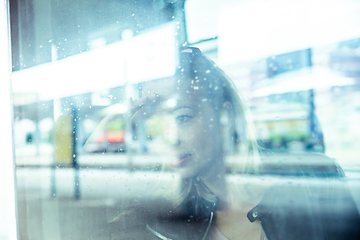 Image showing Woman traveler contemplating outdoor view from window of train. Young lady on commute travel to work sitting in bus or train.