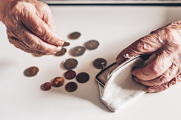 Image showing Detailed closeup photo of elderly 96 years old womans hands counting remaining coins from pension in her wallet after paying bills. Unsustainability of social transfers and pension system.