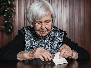 Image showing Portrait of an old woman counting money. The concept of old age, poverty, austerity.