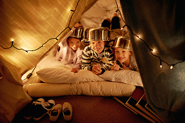 Image showing Kids, portrait and siblings with pot helmet in a fort for fantasy, learning or playing in their home. Happy family, face and children on a floor with tent games, development or smile in a house