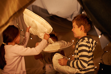 Image showing Children, pillow fight and siblings in a fort with funny, playing or bonding at home together. Family, love and kids in a living room tent with cushion, games or having fun on staycation in house