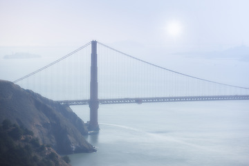 Image showing Golden Gate bridge, fog and ocean at sunrise by road, infrastructure or architecture in nature. Street, highway and hill with rocks, sea or horizon in morning sunshine for transport in San Francisco