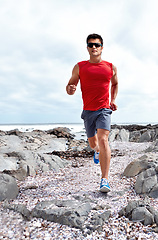 Image showing Athlete male person, running and beach for fitness, health and wellness in activewear and sunglasses. Man, jog and seaside for sport, training and workout exercise for cardio outdoor routine