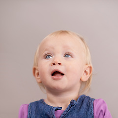 Image showing Thinking, happy baby and cute in studio with expression and playful with curiosity in mock up. Toddler, girl and healthy child with blonde hair, joy or blue eyes and kids fashion by brown background