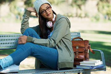 Image showing Thinking, relax and student in park with books for studying, learning and reading outdoors. Education, happy and person with bag, textbooks and headphones on bench for university, campus or college