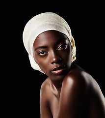 Image showing Serious, portrait and black woman with head wrap, natural makeup or creative beauty aesthetic in studio. Art, skincare and African girl on dark background with scarf, facial cosmetics and confidence.