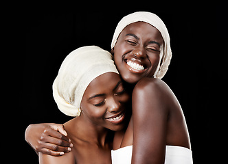 Image showing Black women, head wrap and beauty with hug, skincare and cosmetics in studio with bonding. Girl friends, happy smile and African scarf with wellness and skin glow with makeup and dark background