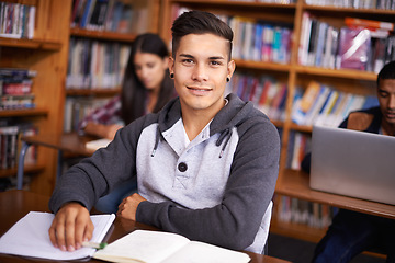 Image showing Young man, portrait or studying in library for test or scholarship on campus for class assignment. University student, face or happy for education or research in books for exam preparation by desk
