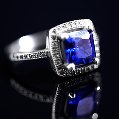 Image showing Sapphire, silver ring and studio by black background for closeup, vintage product and luxury. Tanzanite, blue gemstone and white gold with precious metal for jewelry, shine and glow with reflection