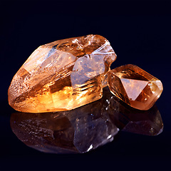 Image showing Orange stone, jewel studio by black background for natural resource, garnet or sparkle for luxury. Rock, gemstone or crystal in closeup for shine, glow and uncut mineral with reflection for wealth