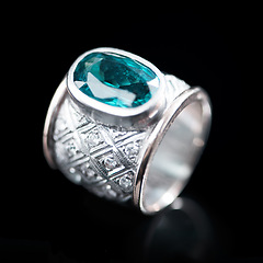 Image showing Green, silver and ring on a black background for luxury gift, expensive and engagement or marriage in studio. Jewelry, diamonds and gemstone or rock in closeup with product texture and emerald color