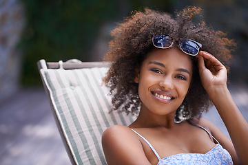 Image showing African, woman and sunbathing and relax, holiday for summer on vacation and sunglasses for time fun. Happy, smile or female person laying on resort deck, comfortable or wellness patio furniture