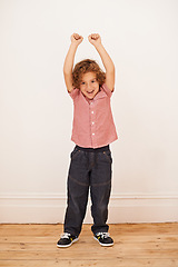 Image showing Excited boy, child and portrait with fist in air by wall in family home for game, winning or success. Kid, happy and playful with smile for victory, cheers and celebration for fun in living room